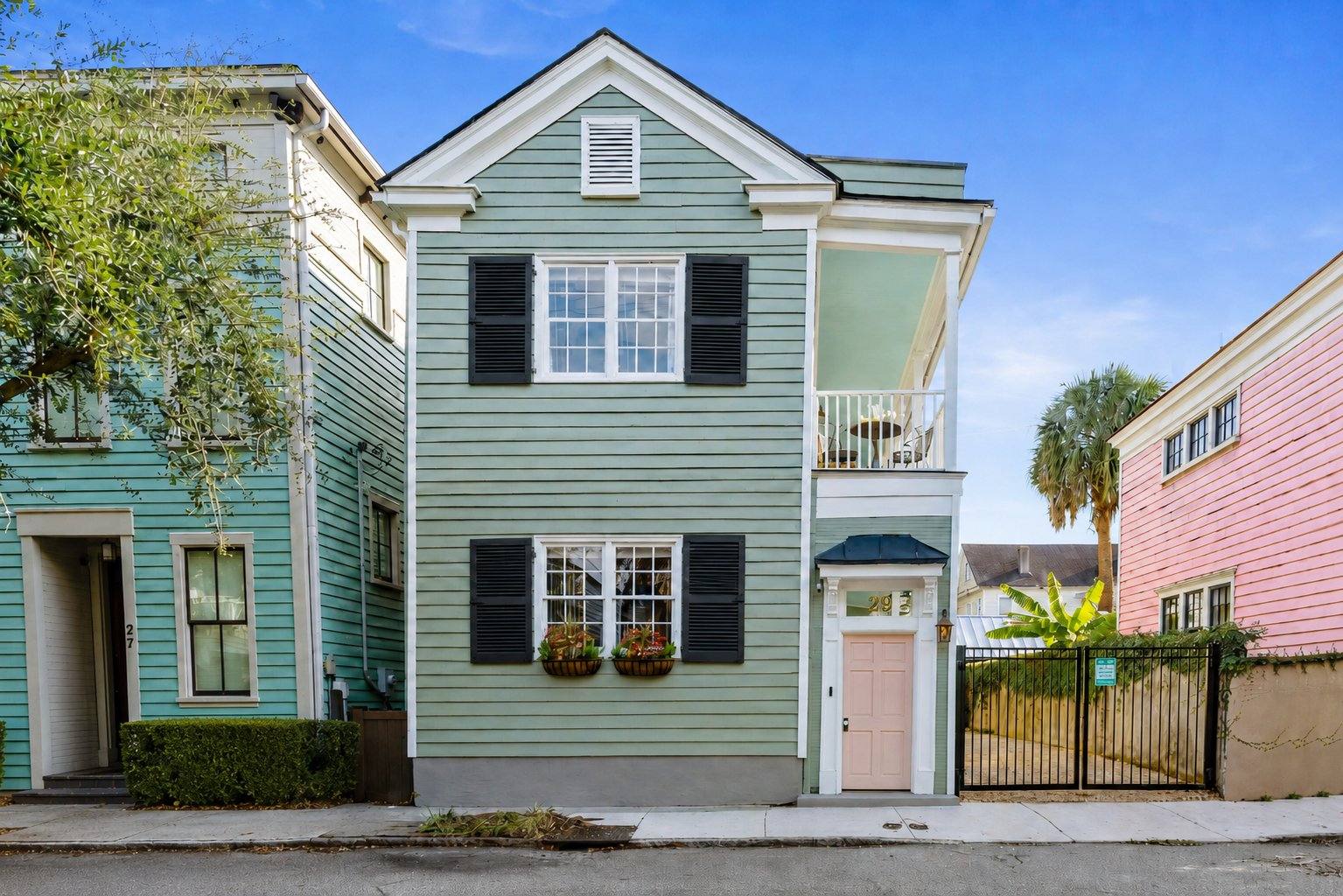 Breezy Palm in daylight, a sage green Charleston single house with a pink door